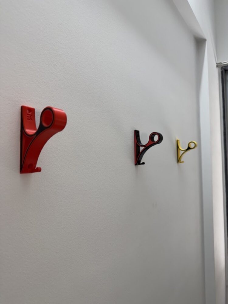 Three mounts in red, red-black and yellow lined up along a white wall.