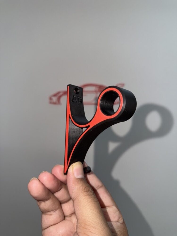Black and orange mount held up in front of a wall with a red car decal.