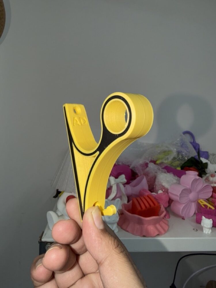 Yellow and black mount held in a hand, workshop shelf behind.